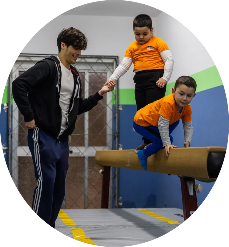 A coach helping two children along a balance beam