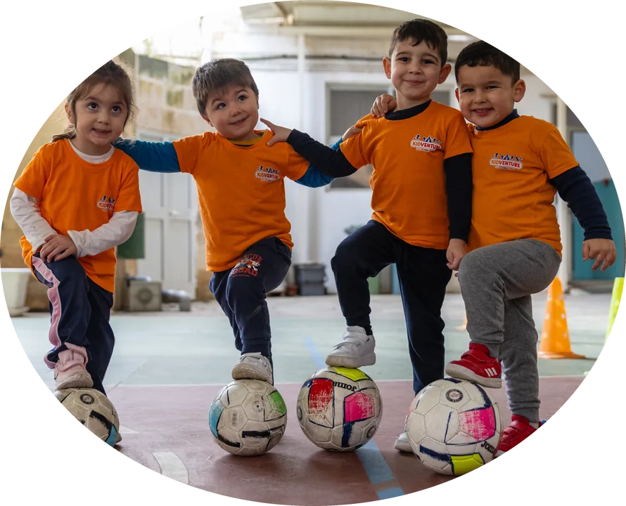 Four children posing with a foot on their footballs