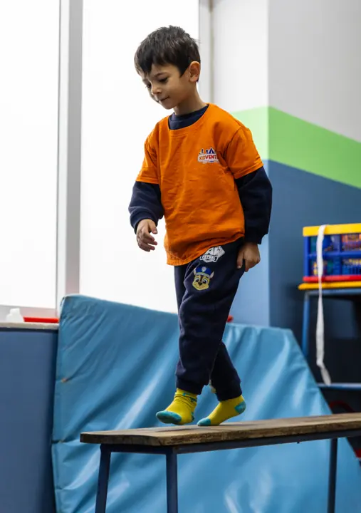 A boy balancing along a bench in the gym