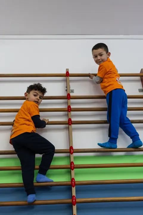 Two boys climbing the wall bars
