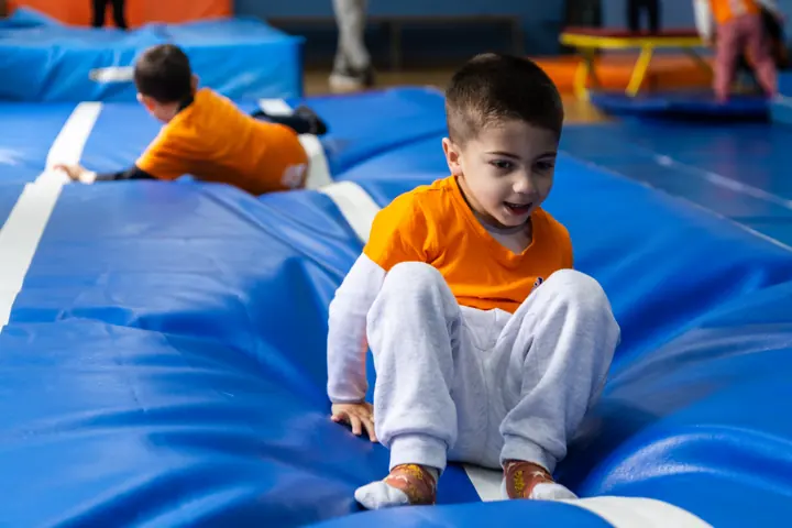 A boy crawling across the gym mats