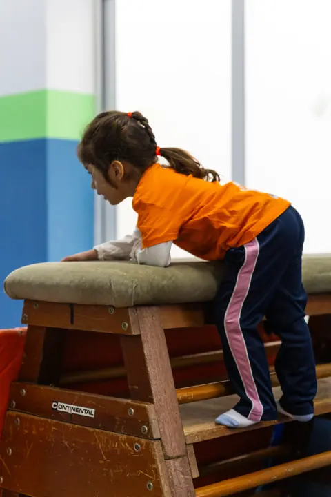 A girl climbing onto a vaulting box