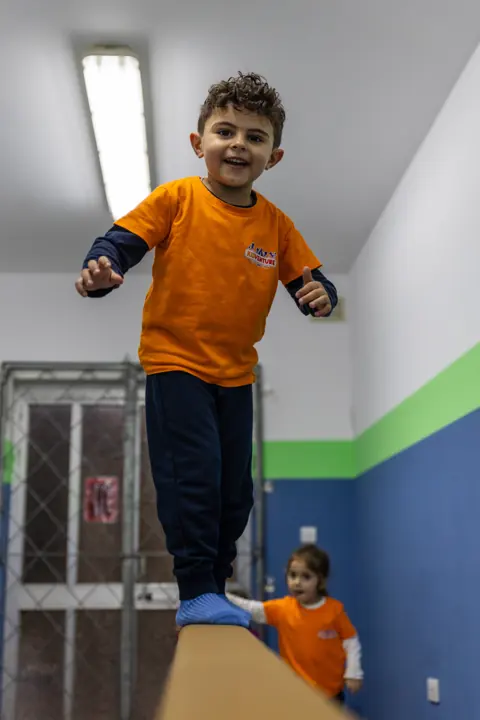 A smiling boy balancing on a beam