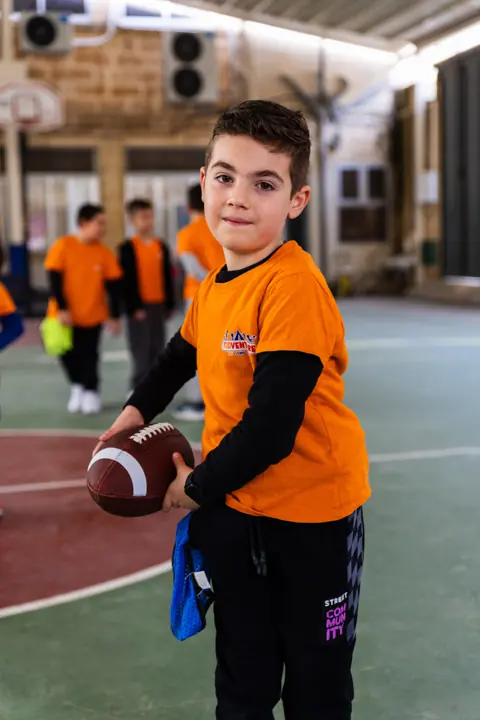 A boy with an American football on the court