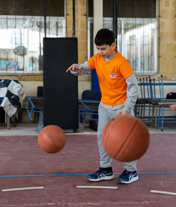 A boy dribbling two basketballs