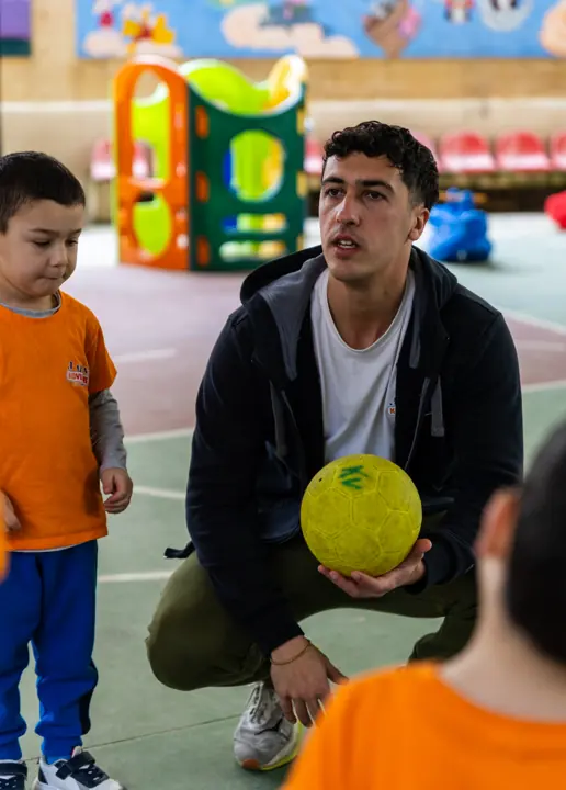 A coach crouching with a ball to explain a game