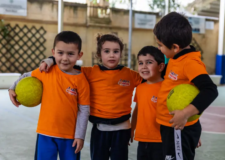 Four friends in KidVenture T-shirts holding balls