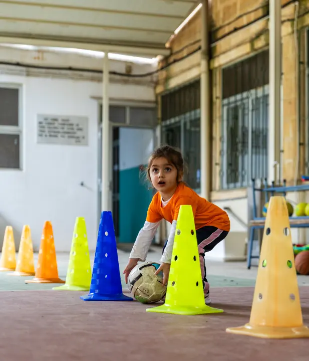 A girl with a football among colourful cones