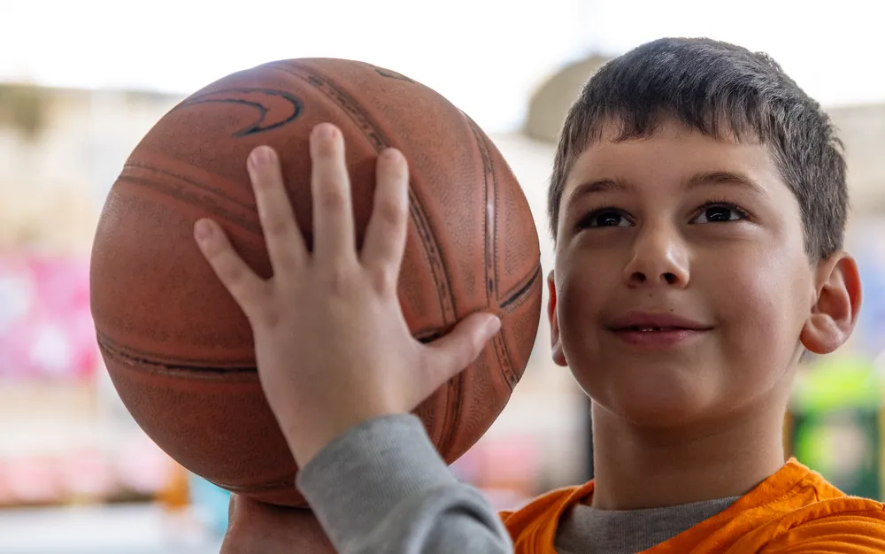 A boy smiling as he gets ready to shoot a basketball