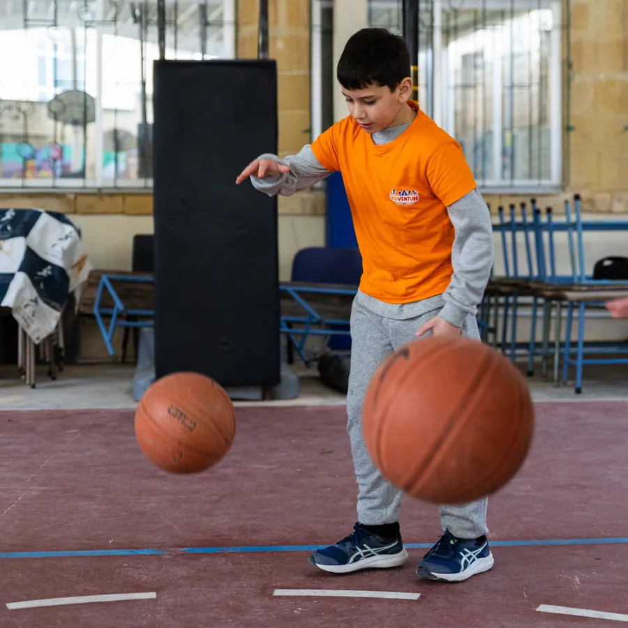 A boy dribbling two basketballs at once