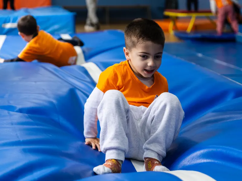 A smiling boy on the soft gym mats