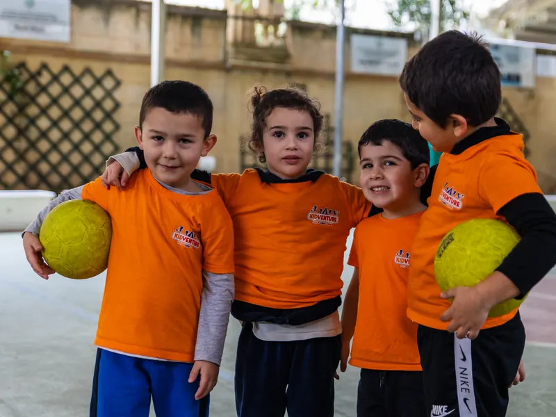 Four friends in KidVenture T-shirts holding balls