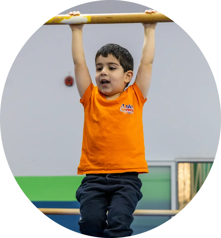 A boy hanging from a gymnastics bar